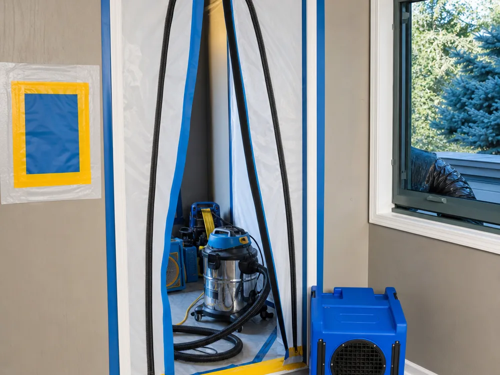 Sealed containment doorway with negative air machine, HEPA vacuum, ducting, and remediation tools